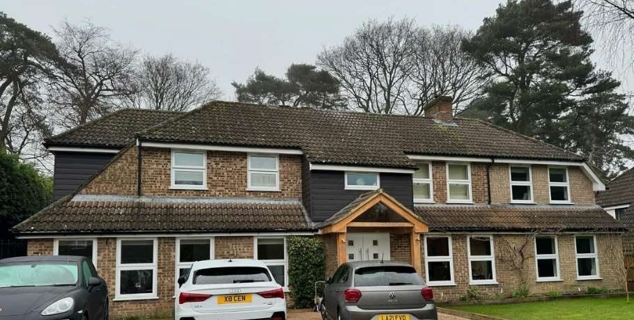 Large residential roof with faded, moss-covered tiles before roof cleaning and coating service in Central Scotland